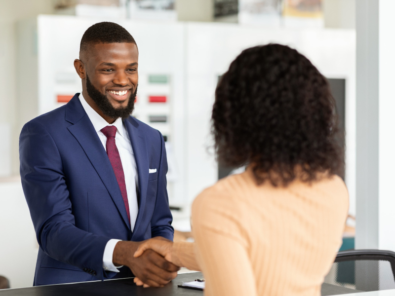 Smiling Car Seller Shaking Hands With Female Customer After Successful Deal, Unrecognizable African American Woman Buying New Vehicle In Dealership Center, Purchasing Automobile In Modern Showroom